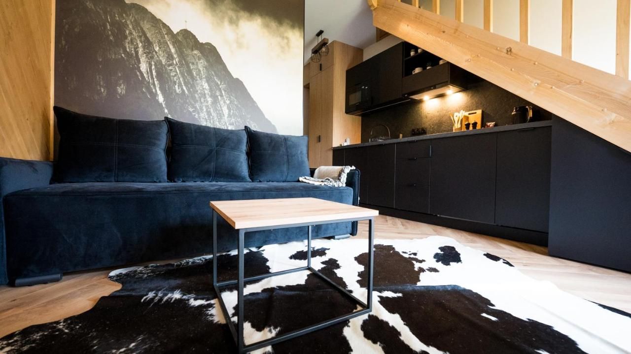 Granatowa sofa i drewniane ściany apartamentu